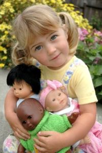 Three year old girl playing with Asian, African American and Caucasian dolls MR
